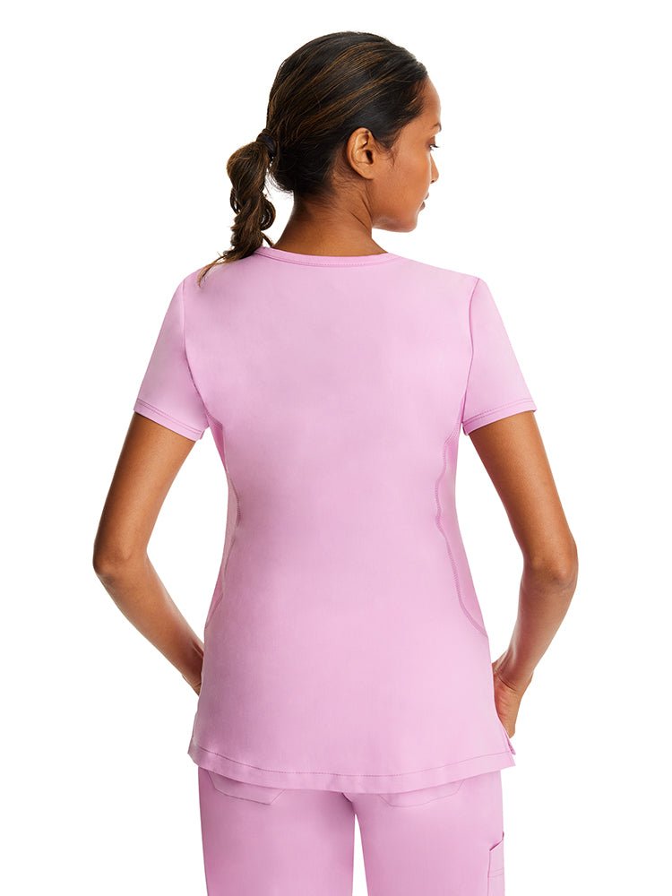 Female healthcare professional wearing a Purple Label Women's Juliet Yoga Scrub Top in "Taffy Pink" with stretch side panels.