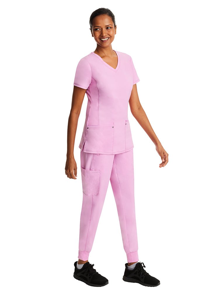 Young woman wearing a Purple Label Women's Juliet Yoga Scrub Top in "Taffy Pink" with side seam vents for a comfotable & flattering fit.