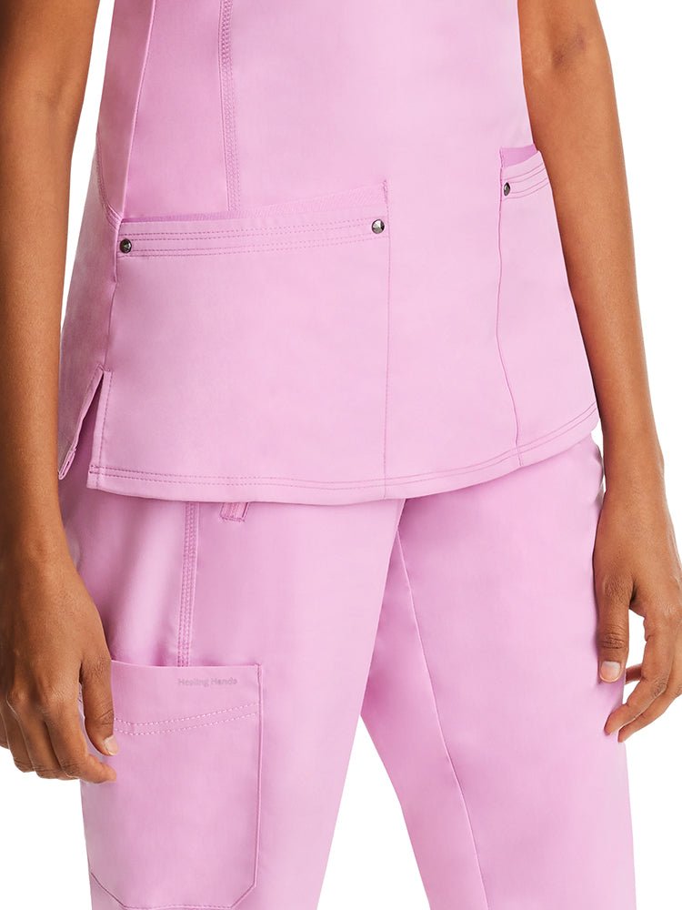 Young woman wearing a Purple Label Women's Juliet Yoga Scrub Top in "Taffy Pink" with 2 front patch pockets.
