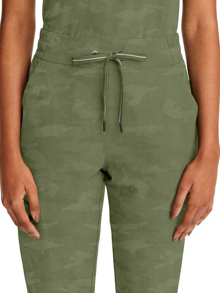 Young woman wearing a pair of Purple Label Women's Tate Camo Joggers in Olive featuring a "Gun Metal" tip with contrast stripe & grommets.