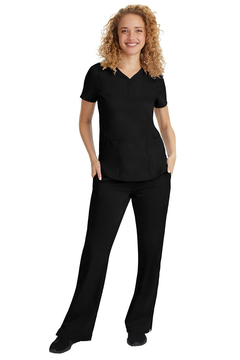 A young female nurse wearing a Purple Label Women's Jane V-Neck Scrub Top in Black featuring a V-neckline & short sleeves.