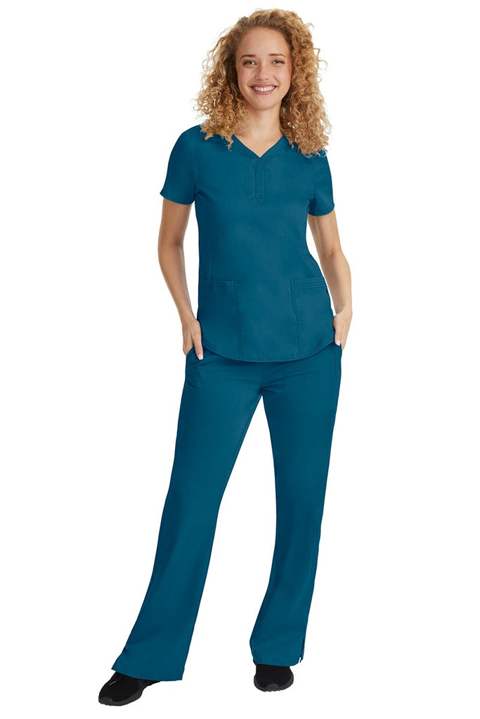 A young female nurse wearing a Purple Label Women's Jane V-Neck Scrub Top in Caribbean featuring a V-neckline & short sleeves.