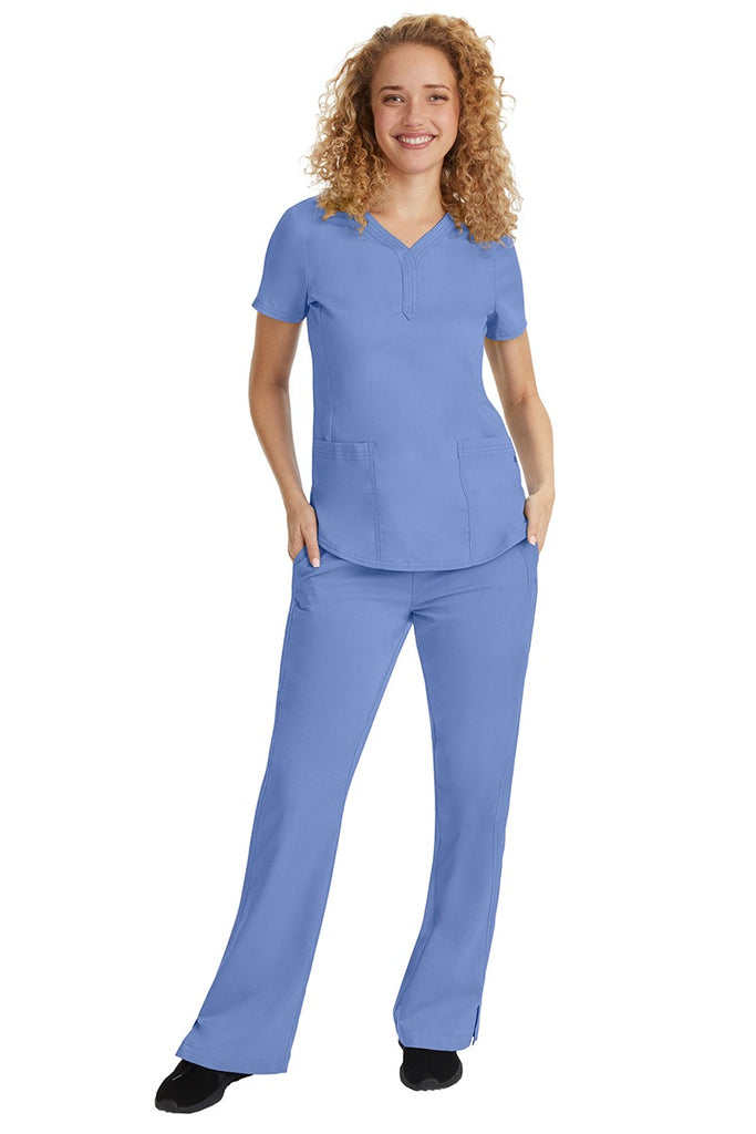 A young female nurse wearing a Purple Label Women's Jane V-Neck Scrub Top in Ceil featuring a V-neckline & short sleeves.
