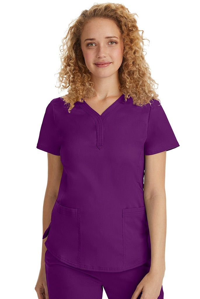 A female Emergency Room Registered Nurse wearing a Purple Label Women's Jane V-Neck Scrub Top in Eggplant featuring front seams for a flattering a fit.