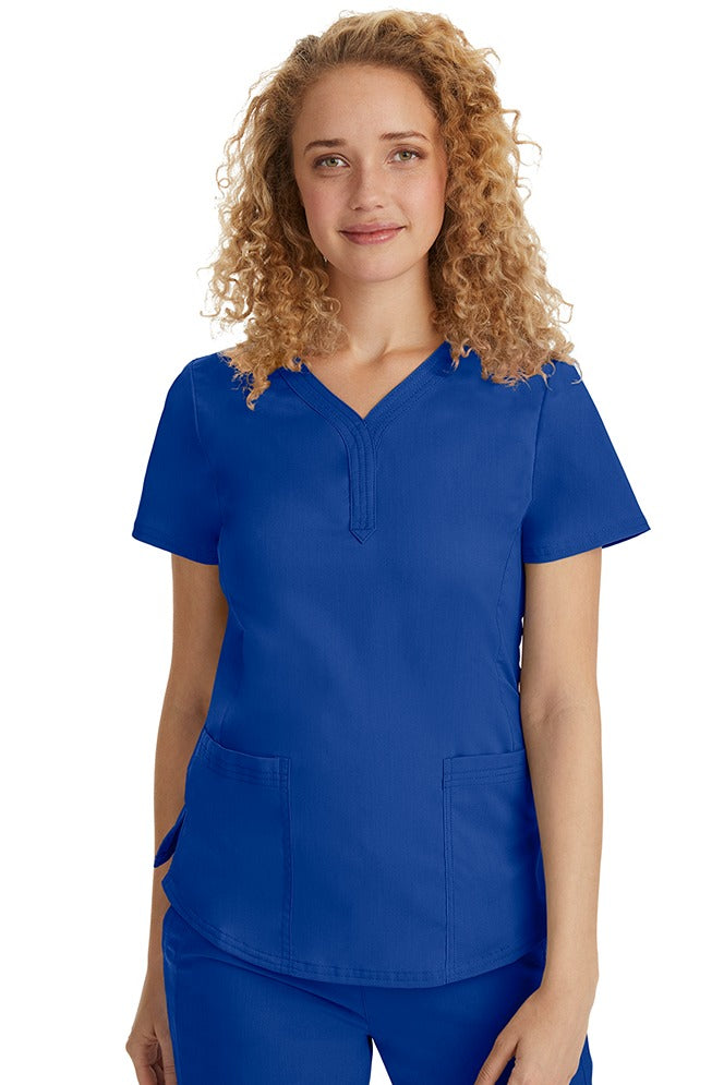 A female Emergency Room Registered Nurse wearing a Purple Label Women's Jane V-Neck Scrub Top in Galaxy Blue featuring front seams for a flattering a fit.