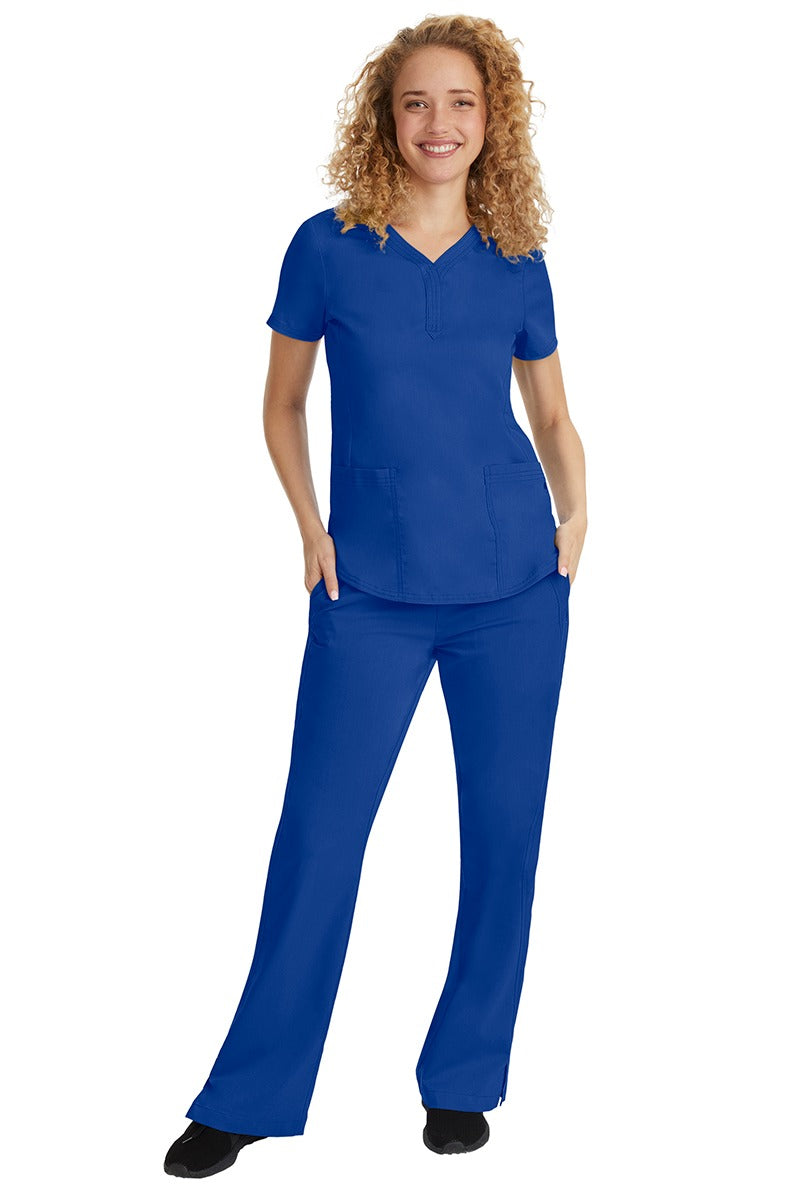 A young female nurse wearing a Purple Label Women's Jane V-Neck Scrub Top in Galaxy Blue featuring a V-neckline & short sleeves.