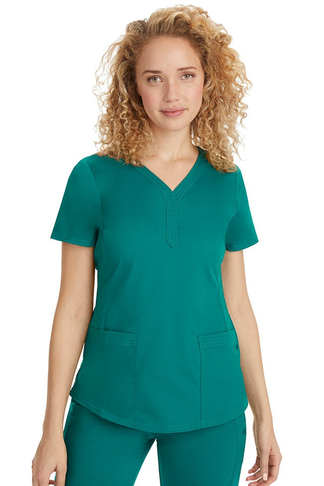 A female RN wearing a Purple Label Women's Jane V-Neck Scrub Top from Healing Hands in Hunter Green featuring hem slits for additional range of motion.