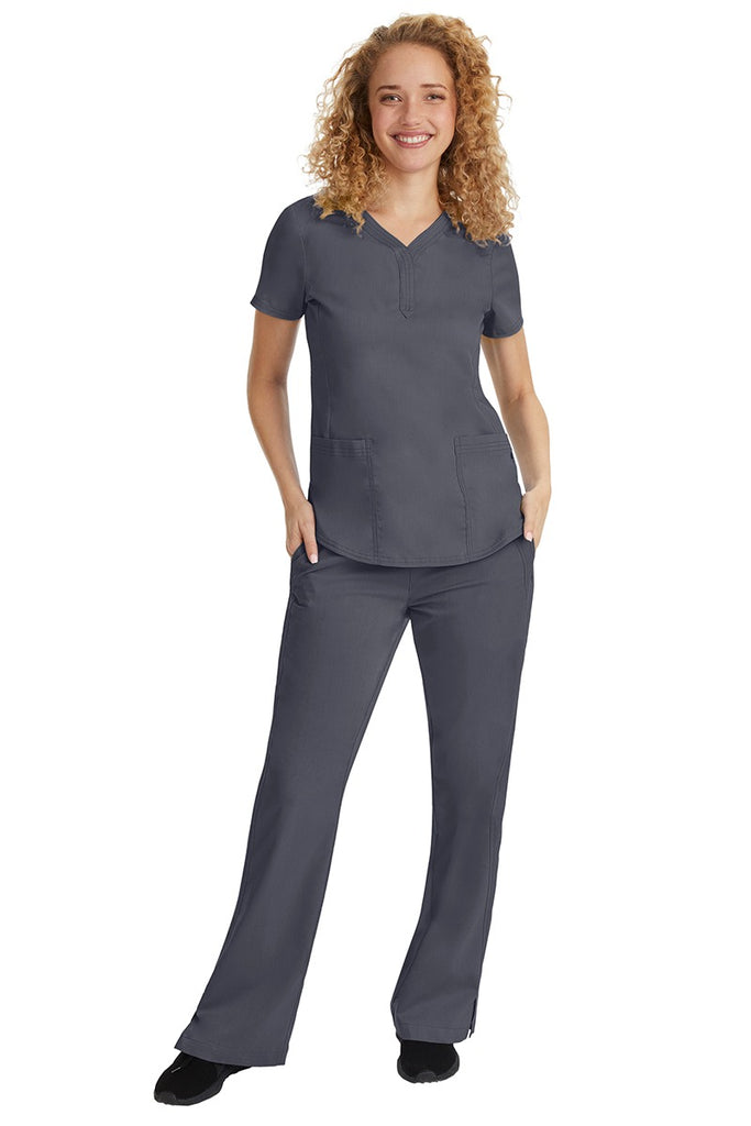 A young female nurse wearing a Purple Label Women's Jane V-Neck Scrub Top in Pewter featuring a V-neckline & short sleeves.
