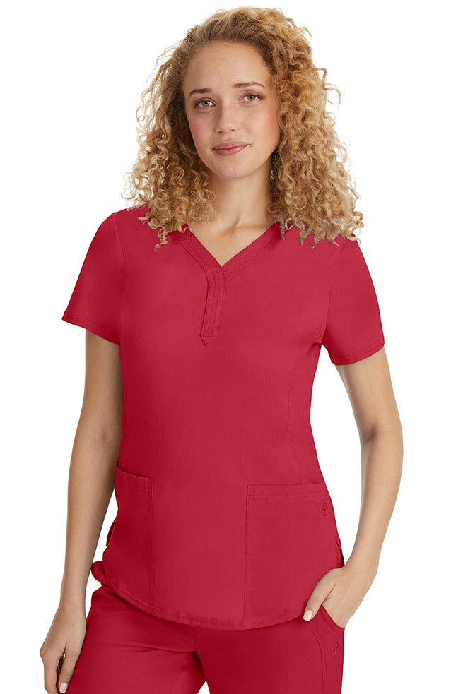 A female RN wearing a Purple Label Women's Jane V-Neck Scrub Top from Healing Hands in Red featuring hem slits for additional range of motion.