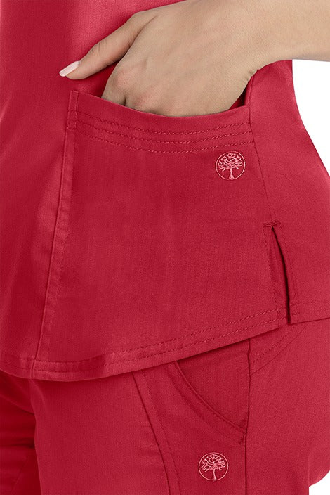 A female healthcare worker wearing a Purple Label Women's Jane V-Neck Scrub Top in Red featuring triple needle stitch detail at the pockets.