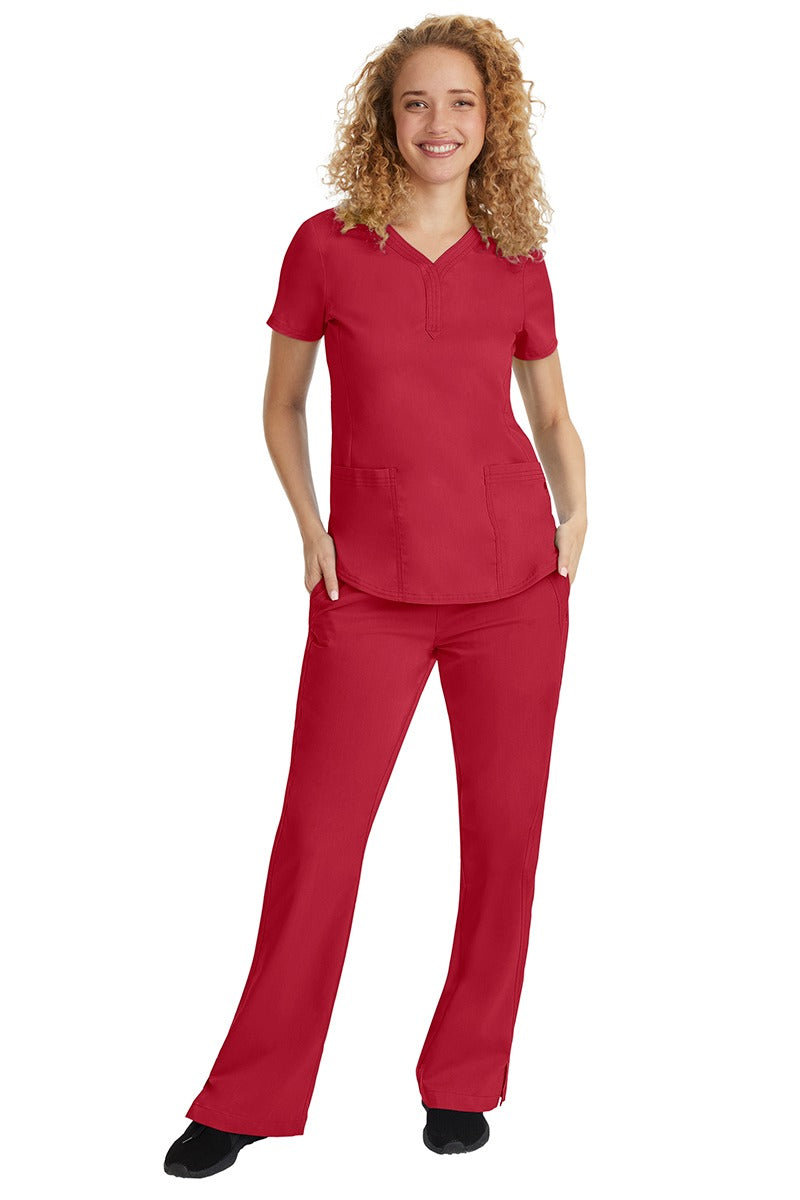 A young female nurse wearing a Purple Label Women's Jane V-Neck Scrub Top in Red featuring a V-neckline & short sleeves.