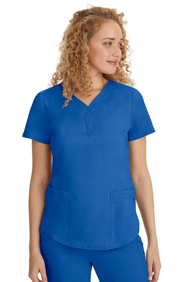 A young female healthcare professional wearing a Purple Label Women's Jane V-Neck Scrub Top in Royal featuring 2 front patch pockets.