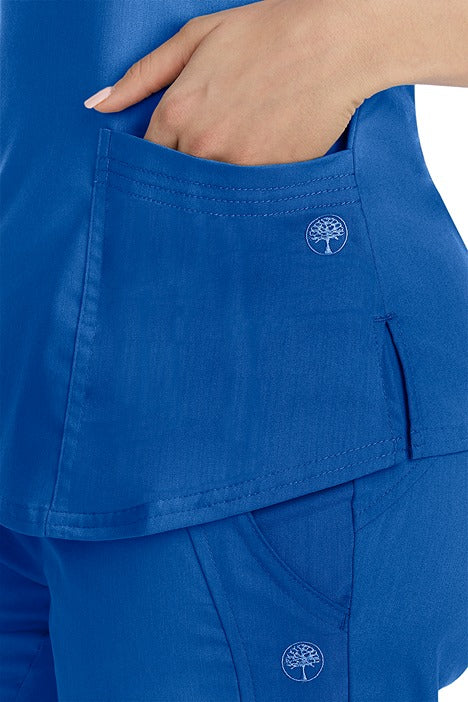 A female healthcare worker wearing a Purple Label Women's Jane V-Neck Scrub Top in Royal featuring triple needle stitch detail at the pockets.