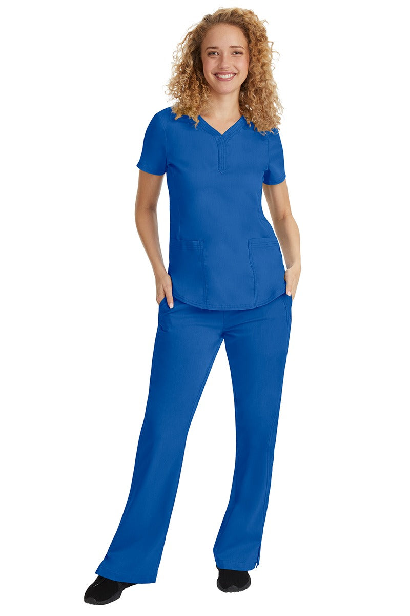 A young female nurse wearing a Purple Label Women's Jane V-Neck Scrub Top in Royal featuring a V-neckline & short sleeves.