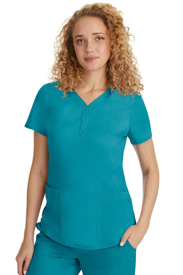 A female RN wearing a Purple Label Women's Jane V-Neck Scrub Top from Healing Hands in Teal  featuring hem slits for additional range of motion.