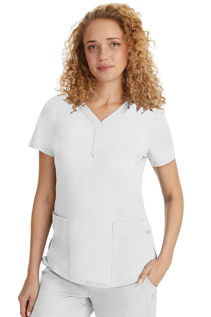 A female RN wearing a Purple Label Women's Jane V-Neck Scrub Top from Healing Hands in White  featuring hem slits for additional range of motion.