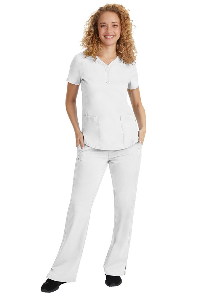 A young female nurse wearing a Purple Label Women's Jane V-Neck Scrub Top in White featuring a V-neckline & short sleeves.