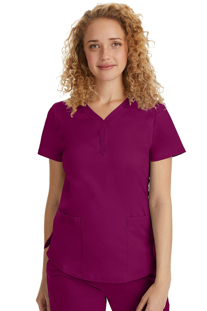 A female Emergency Room Registered Nurse wearing a Purple Label Women's Jane V-Neck Scrub Top in Wine featuring front seams for a flattering a fit.
