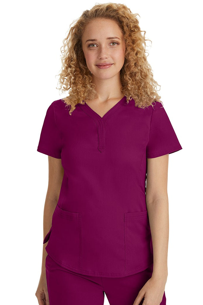 A female Emergency Room Registered Nurse wearing a Purple Label Women's Jane V-Neck Scrub Top in Wine featuring front seams for a flattering a fit.