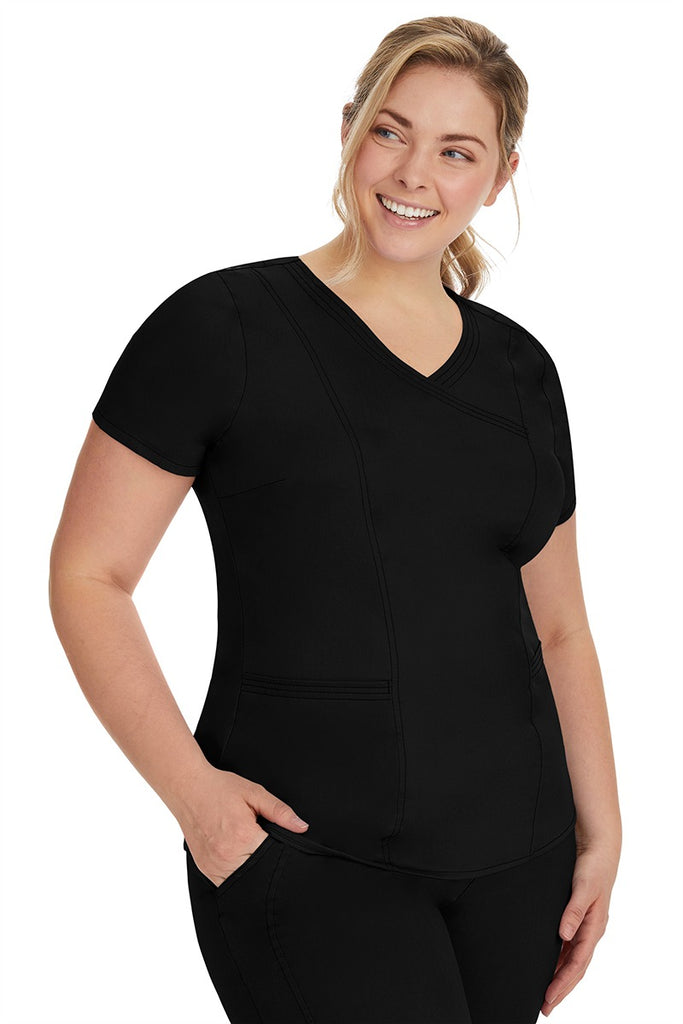 A frontward facing image of a young woman wearing a Purple Label Women's Jordan Crossover Scrub Top in Black featuring front darts.