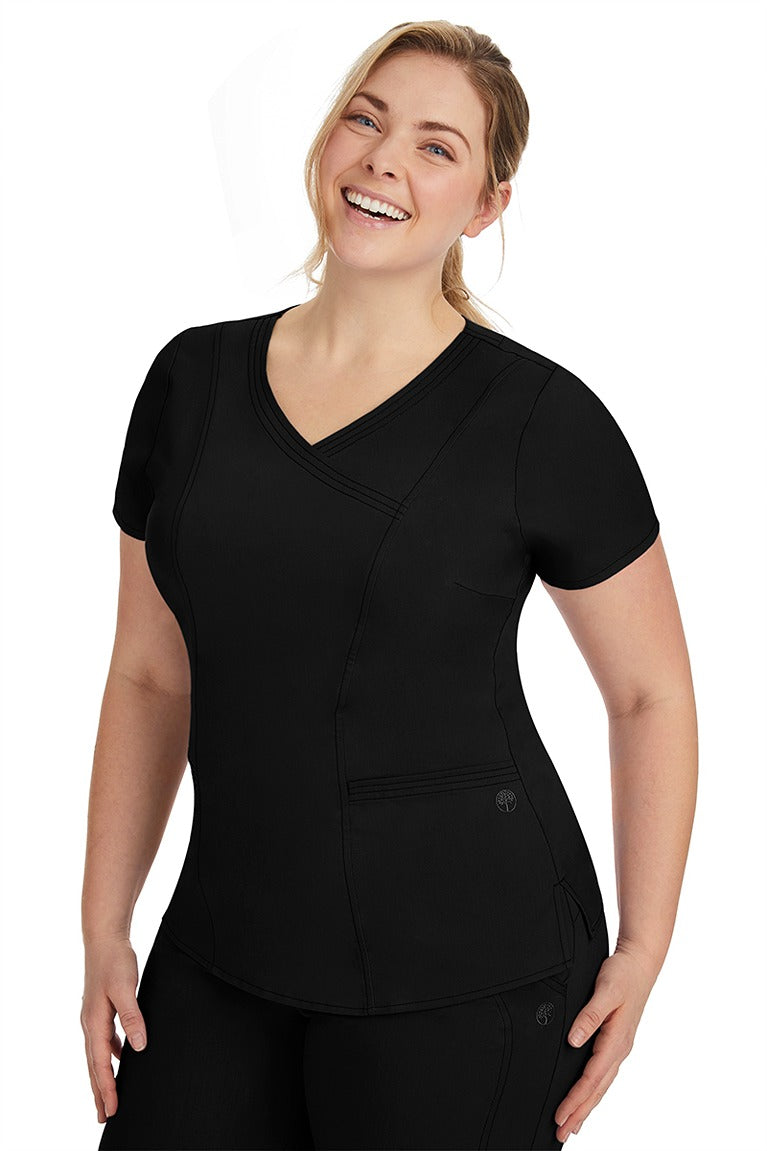 A lady nurse wearing the Purple Label Women's Jordan Crossover Scrub Top in Black featuring side seam vents & side slits for increased breathability & range of motion.