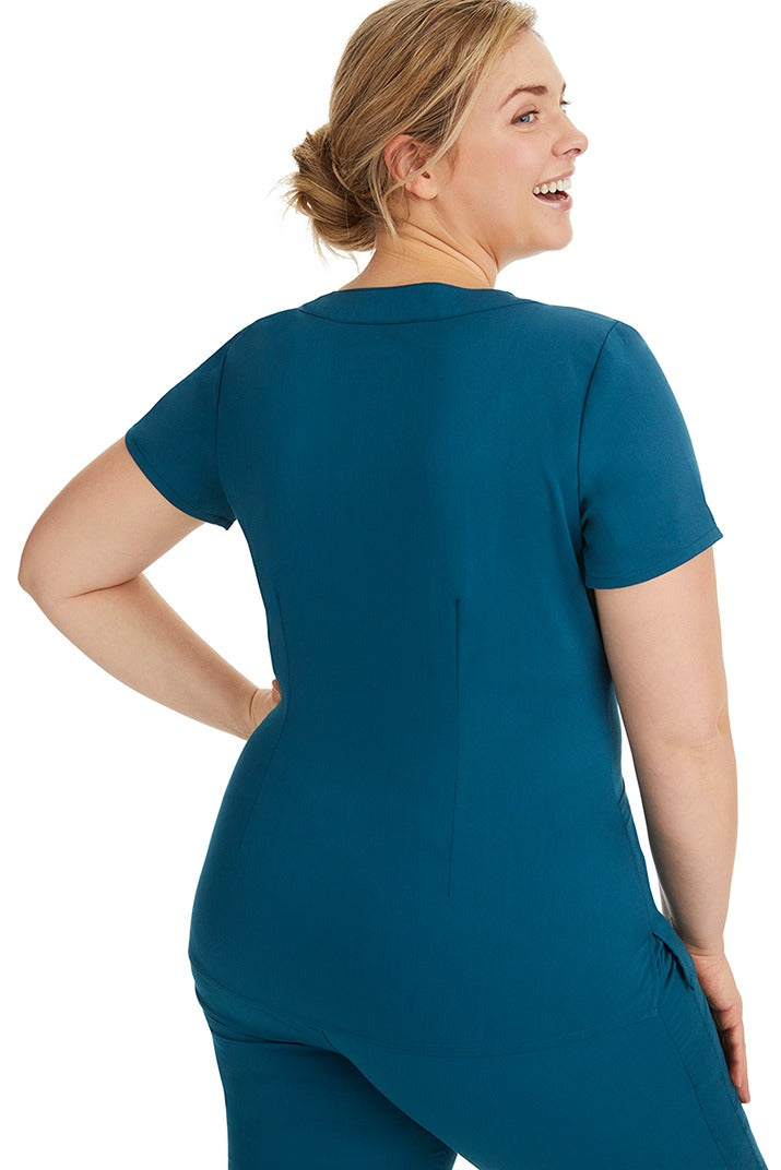 A female LPN wearing a Purple Label Women's Jordan Crossover Scrub Top in Caribbean featuring a unique stretch fabric made of 80% polyester/17% rayon/3% spandex.