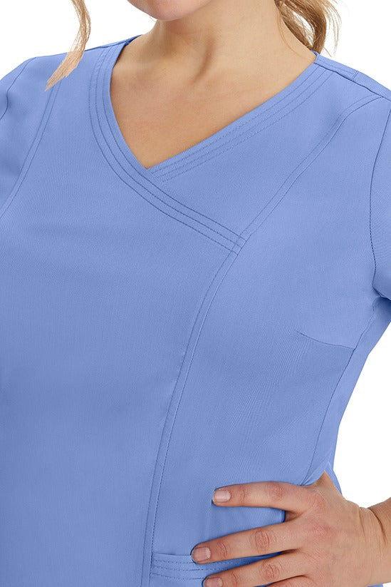 A young healthcare professional wearing a Purple Label Women's Jordan Crossover Top in Ceil featuring triple needle stitching details throughout.