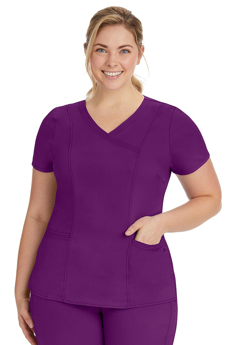 A young lady nurse wearing a Purple Label Women's Jordan Crossover Scrub Top in Eggplant featuring a "Y" neckline.