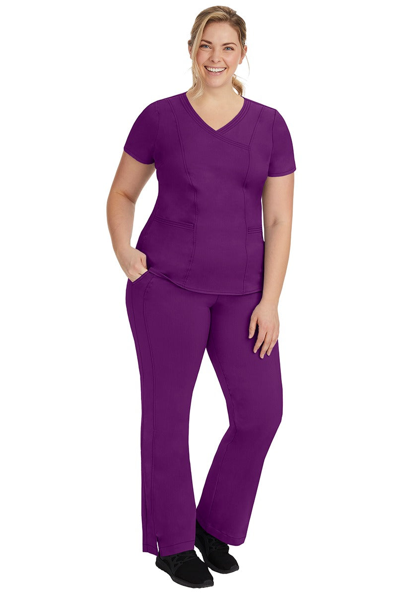 A young female nurse wearing a Women's Jordan Crossover Scrub Top from Purple Label by Healing Hands in Eggplant.