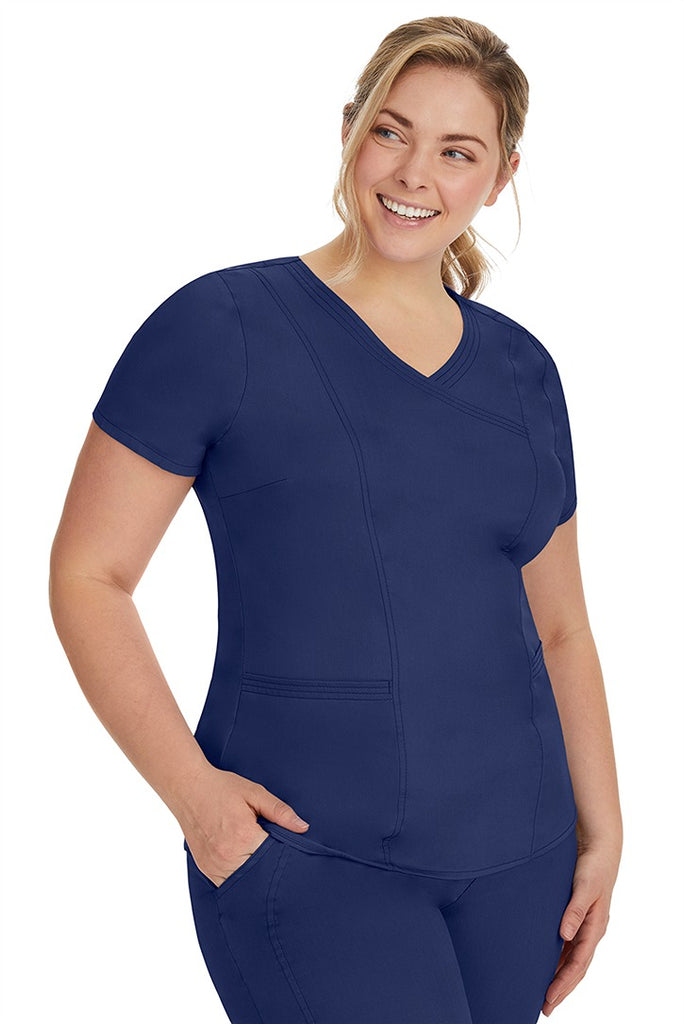 A lady nurse wearing the Purple Label Women's Jordan Crossover Scrub Top in Navy featuring side seam vents & side slits for increased breathability & range of motion.