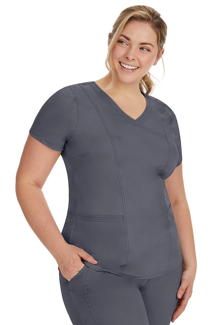 A lady nurse wearing the Purple Label Women's Jordan Crossover Scrub Top in Pewter  featuring side seam vents & side slits for increased breathability & range of motion.