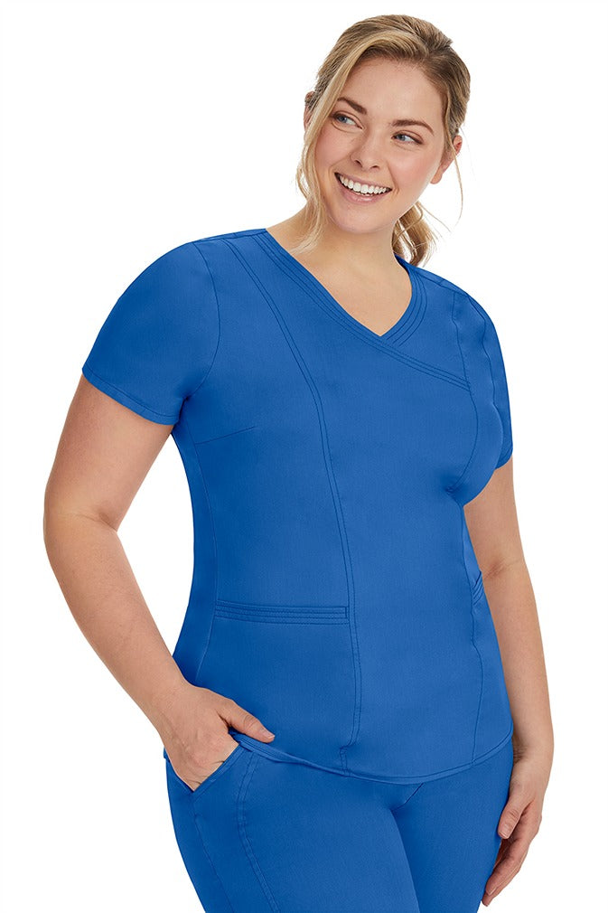 A lady nurse wearing the Purple Label Women's Jordan Crossover Scrub Top in Royal  featuring side seam vents & side slits for increased breathability & range of motion.