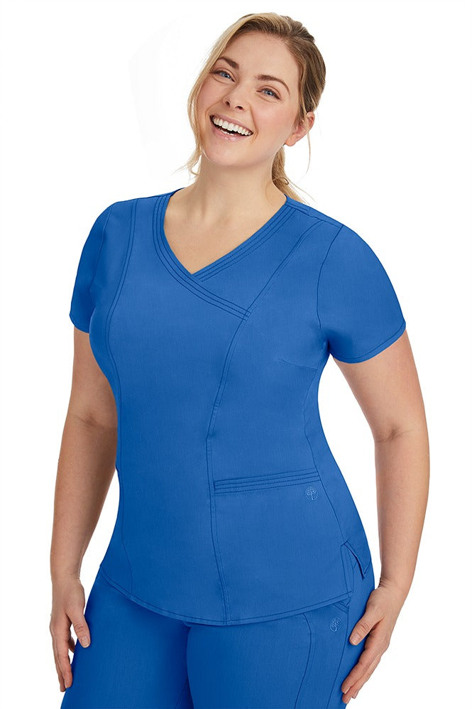 A frontward facing image of a young woman wearing a Purple Label Women's Jordan Crossover Scrub Top in Royal  featuring front darts.