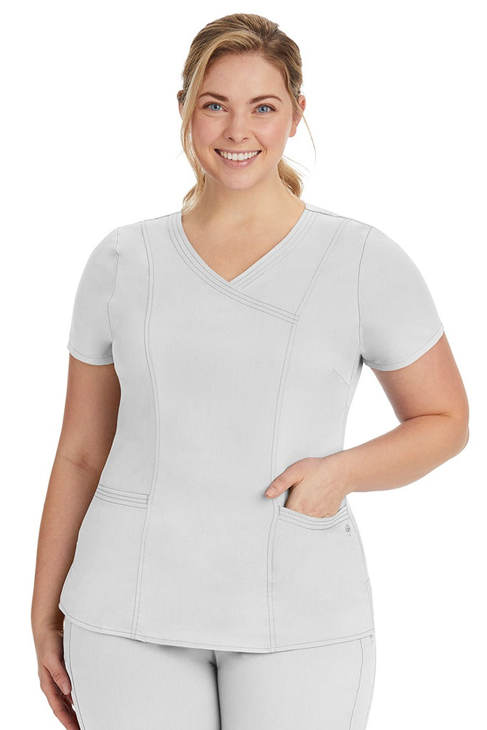A young lady nurse wearing a Purple Label Women's Jordan Crossover Scrub Top in White featuring a "Y" neckline.