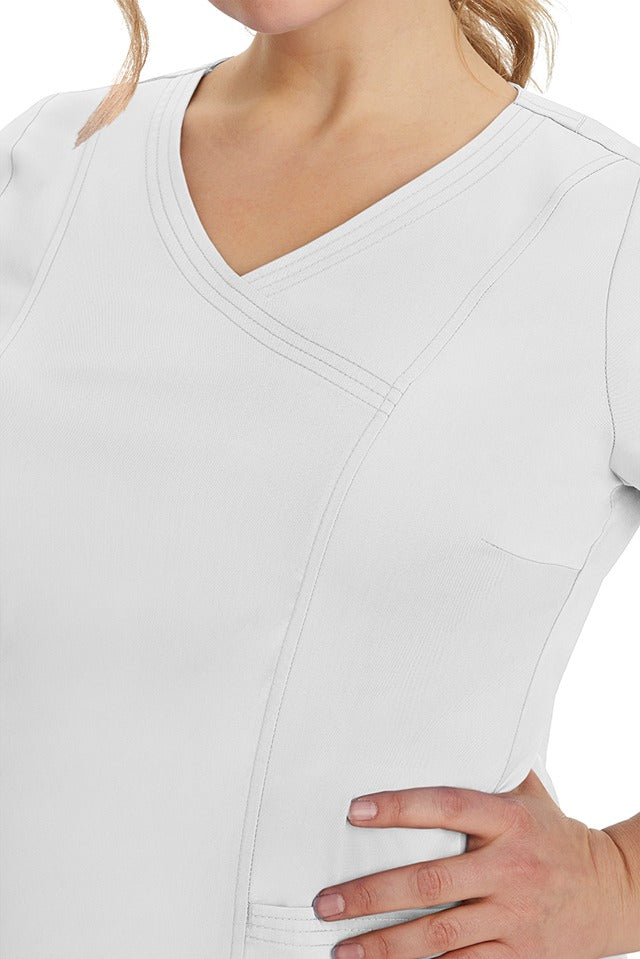 A young healthcare professional wearing a Purple Label Women's Jordan Crossover Top in White featuring triple needle stitching details throughout.