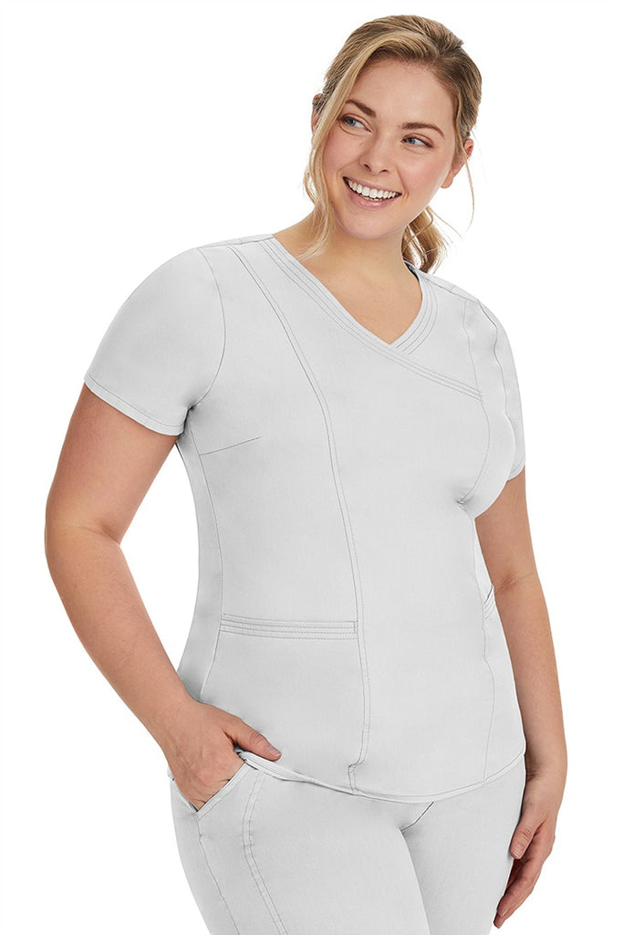 A lady nurse wearing the Purple Label Women's Jordan Crossover Scrub Top in White  featuring side seam vents & side slits for increased breathability & range of motion.