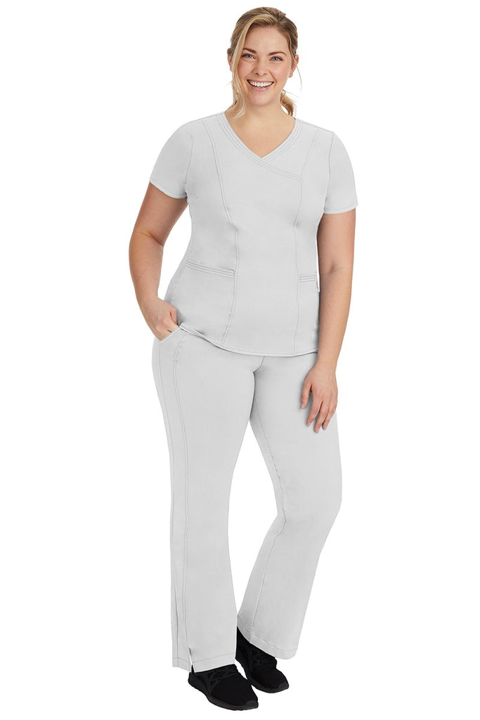 A young female nurse wearing a Women's Jordan Crossover Scrub Top from Purple Label by Healing Hands in White.