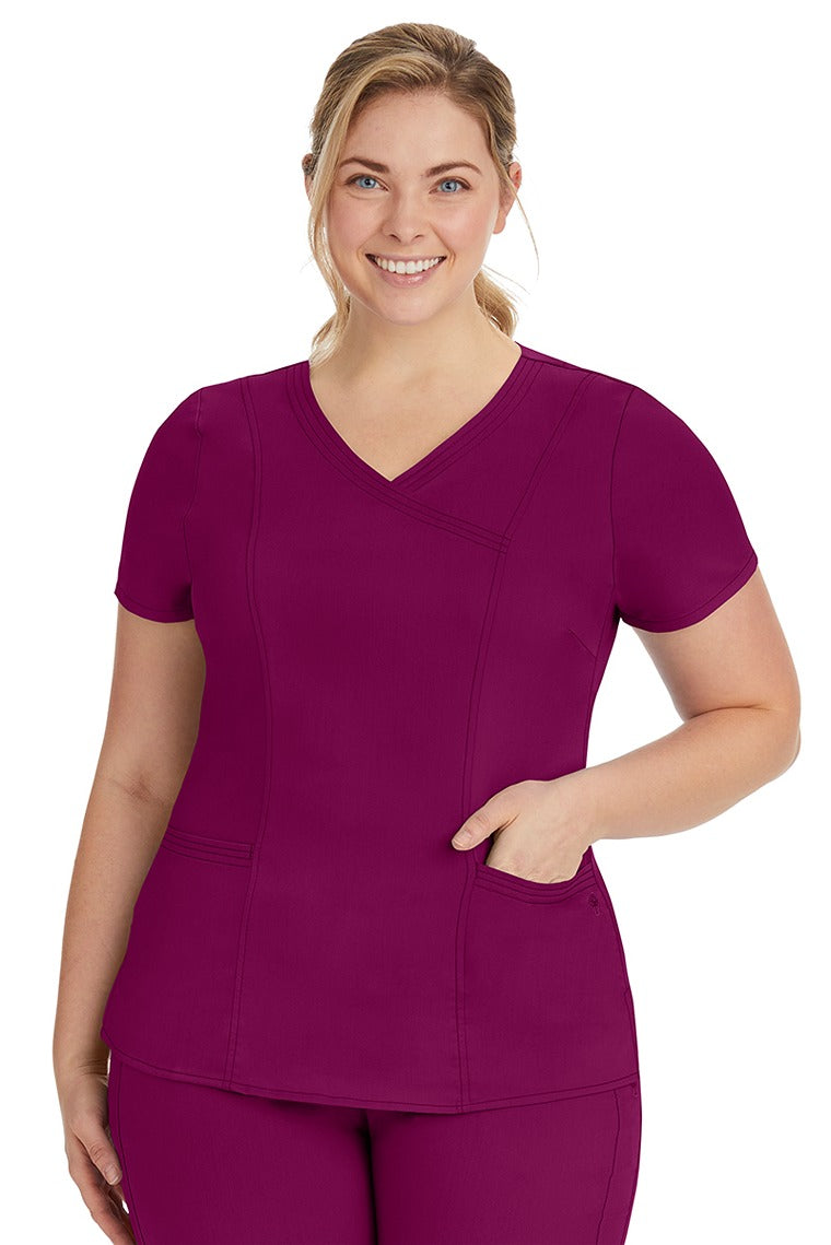 A young lady nurse wearing a Purple Label Women's Jordan Crossover Scrub Top in Wine featuring a "Y" neckline.