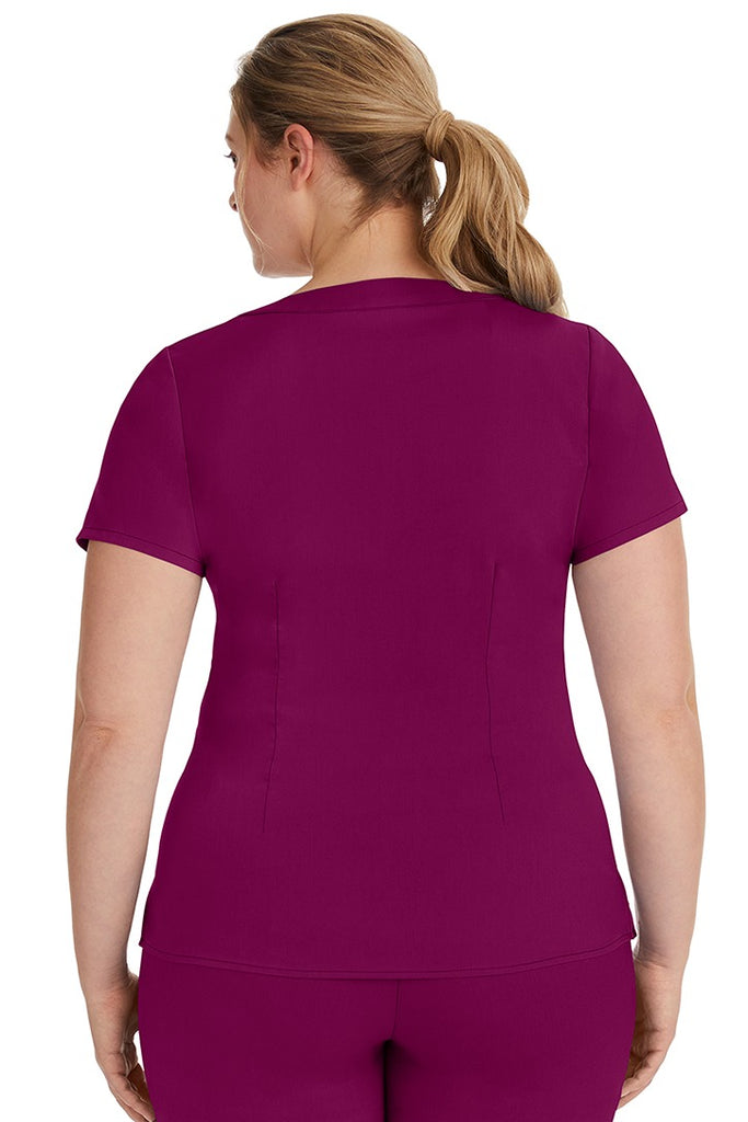 A female LPN wearing a Purple Label Women's Jordan Crossover Scrub Top in Wine featuring a unique stretch fabric made of 80% polyester/17% rayon/3% spandex.