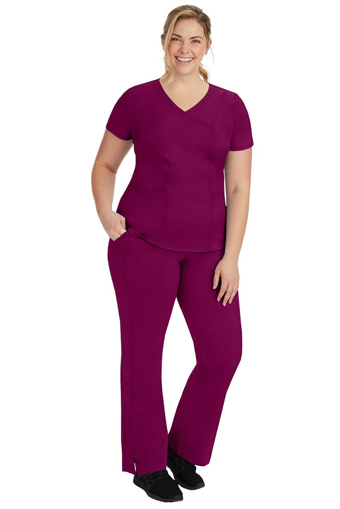 A young female nurse wearing a Women's Jordan Crossover Scrub Top from Purple Label by Healing Hands in Wine.