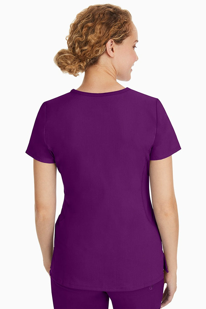 A female CNA wearing a Purple Label Women's Juliet Yoga Scrub Top in Eggplant featuring a medium center back length of 24".