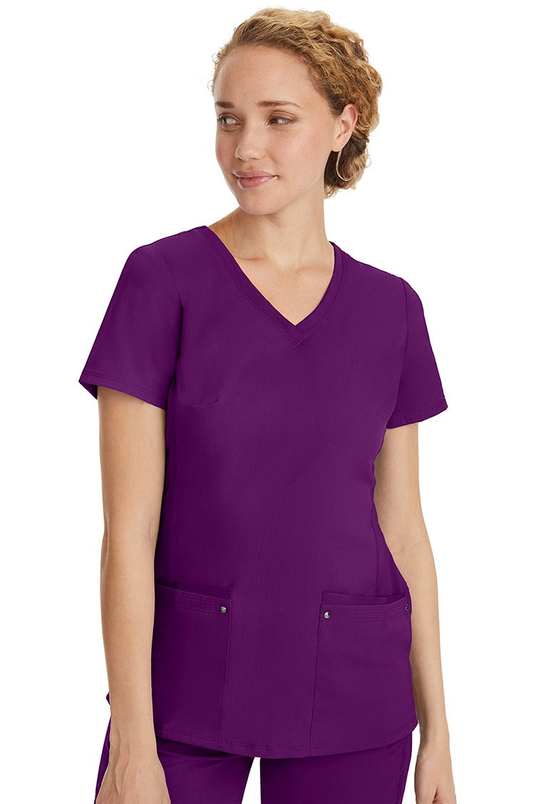 A lady nurse wearing a Purple Label Women's Juliet Yoga Scrub Top in Eggplant featuring a super comfortable stretch fabric made of 77% polyester/20% rayon/3% spandex.