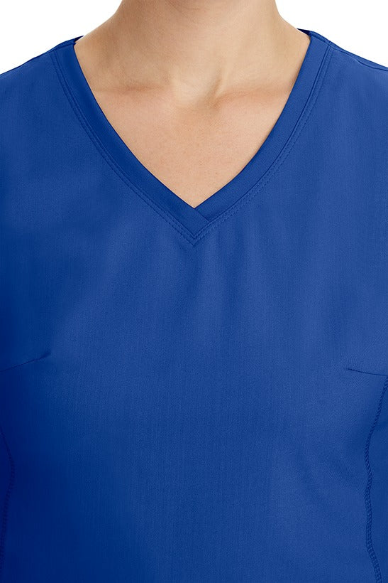 A young healthcare professional wearing a Purple Label Women's Juliet Yoga Scrub Top in Galaxy Blue featuring a modern fit.
