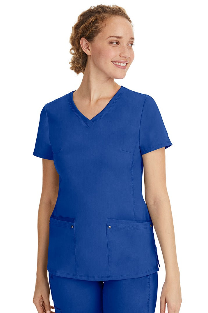 A female healthcare professional wearing a Women's Juliet Yoga Scrub Top from Purple Label in Galaxy Blue featuring a side stretch panels.