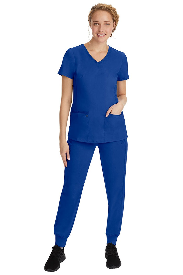A young female nurse wearing a Purple Label Women's Juliet Yoga Scrub Top by Healing Hands in Galaxy Blue featuring a v-neckline.