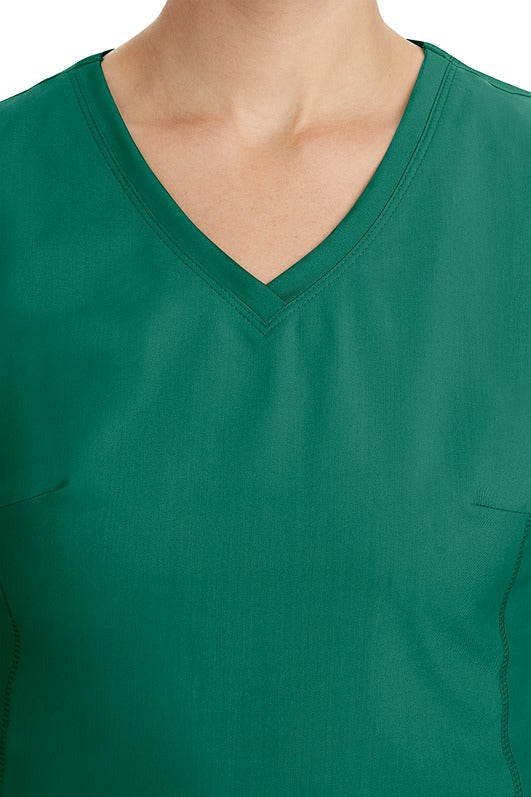 A young healthcare professional wearing a Purple Label Women's Juliet Yoga Scrub Top in Hunter Green featuring a modern fit.