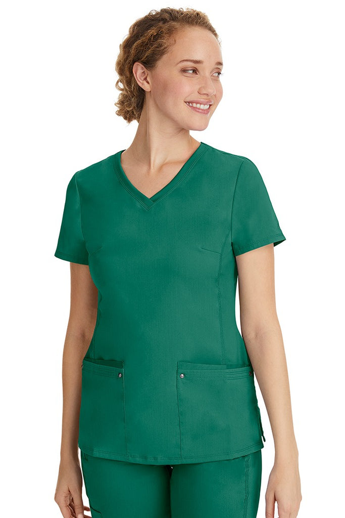 A female healthcare professional wearing a Women's Juliet Yoga Scrub Top from Purple Label in Hunter featuring a side stretch panels.