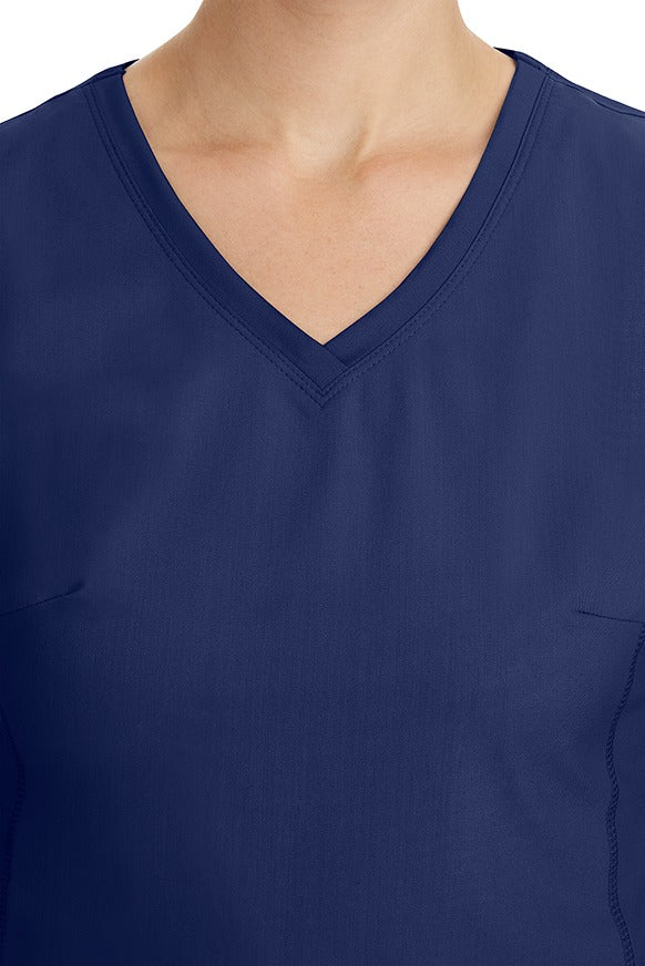 A young healthcare professional wearing a Purple Label Women's Juliet Yoga Scrub Top in Navy featuring a modern fit.
