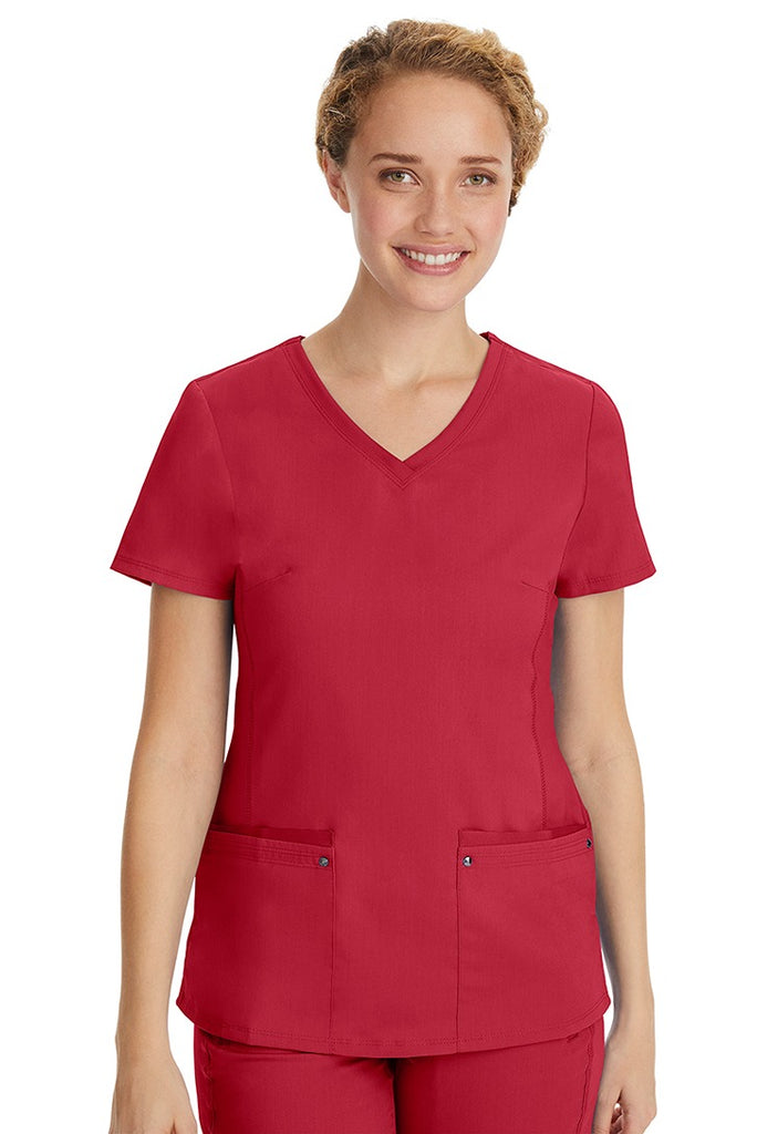 A young LPN wearing a Purple Label Women's Juliet Yoga Scrub Top in Red featuring 2 front patch pockets.