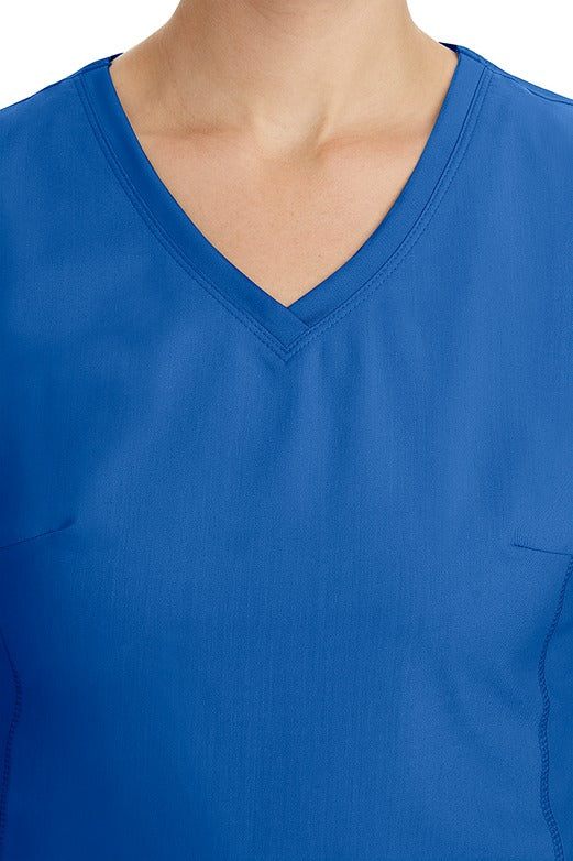 A young healthcare professional wearing a Purple Label Women's Juliet Yoga Scrub Top in Royal featuring a modern fit.